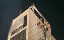 Một người có biểu hiện mất kiểm soát ngồi trên nóc tòa nhà 4 tầng