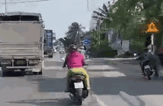 CLIP: Người phụ nữ chạy xe máy đánh võng trước đầu xe tải trên đường phố