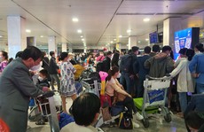 Hành khách vạ vật ở sân bay Tân Sơn Nhất rạng sáng 7-2 chờ lấy hành lý, gọi xe