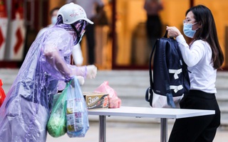 Người dân mặc áo mưa tiếp tế lương thực vào trung tâm thương mại bị phong toả