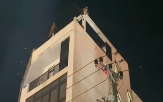 Một người có biểu hiện mất kiểm soát ngồi trên nóc tòa nhà 4 tầng